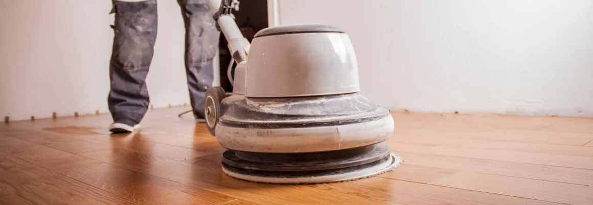 Handwerker ölt Parkettboden mit großer Poliermaschine.